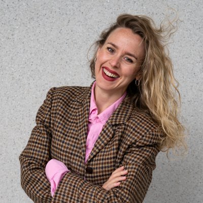 Foto av Ragnhild Brochmann. Hun har på en rutete blazer, rosa skjorte og blomstrete skjørt. 