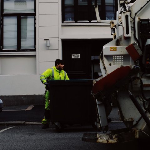 Renovasjonsarbeider ved søppelbil.