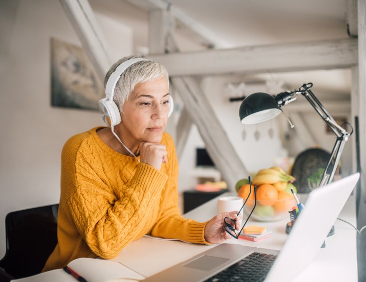 Jvinne sitter med headset og ser på PC